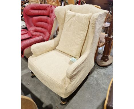 Wingback armchair in the George III manner, with pale yellow loose covers, on front turned baluster legs and castors, 107cm h