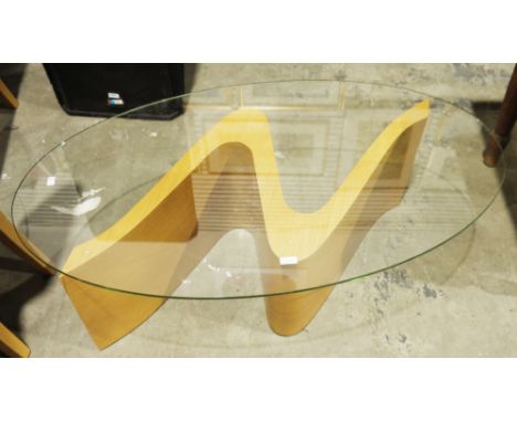 Tom Schneider Wave coffee table, the oval glass top on an S-scroll pale oak plinth base, 39cm high x 117.5cm long x 66cm wide