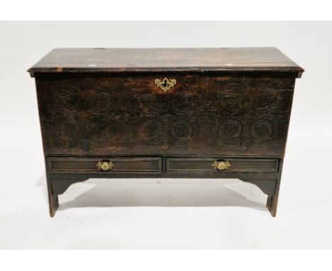 17th century oak plank coffer, the hinged lid opening to a candle box, the carved front panel over two shallow drawers with m
