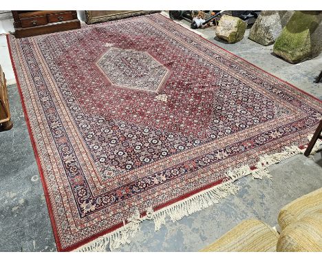 Large Eastern red ground carpet with central stepped lozenge on geometric pattern field, geometric spandrels and multiple flo