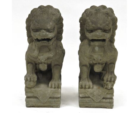 Pair of 20th century Chinese grey stone buddhist lions, each modelled in the Archaic style with front paw on a brocaded ball 