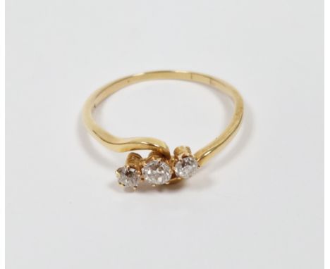 Yellow metal and diamond cross-over ring, comprising a row of three claw-set brilliant cut round diamonds, size V 1/2, 2.6 gr
