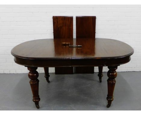 A 19th century mahogany extending dining table, the moulded top on turned supports terminating in ceramic castors complete wi