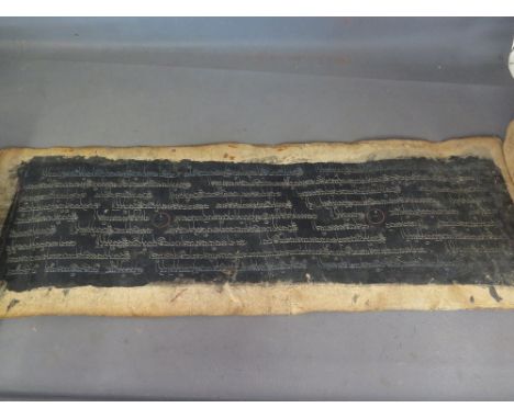 A 17th century Tibetan manuscript page written in silver ink on a black background on a page made from mulberry leaves