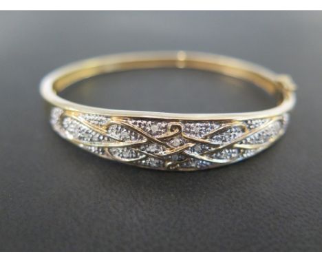 A 9 ct gold and diamond hinged bangle set with numerous diamonds within a white gold illusion setting and yellow gold lattice