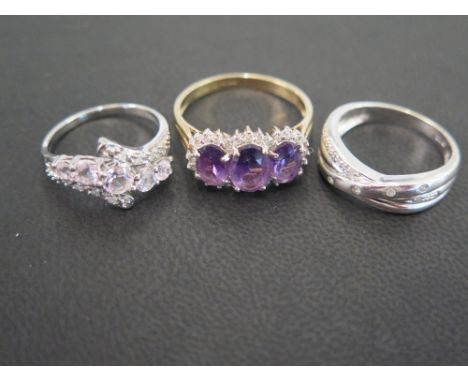 Three 9 ct gold dress rings - one set with three oval amethyst stones surrounded by small diamonds in white gold setting with