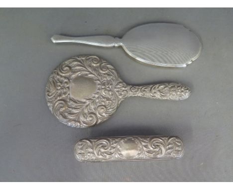 Two silver hallmarked hand mirrors, one with embossed decoration, one with engine turned decoration and one brush embossed de