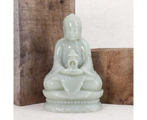 A Chinese jade Buddha,seated cross-legged on a double lotus pedestal, his hands clasped in his lap carrying a shrine, the sto