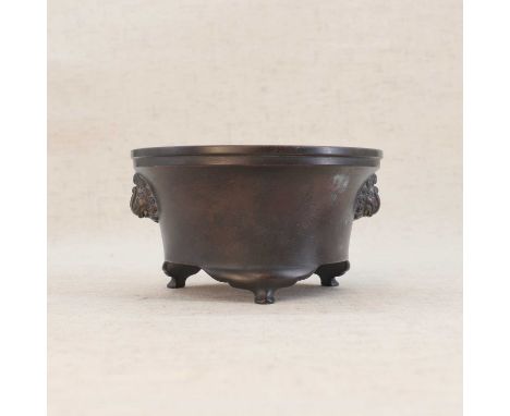 A Chinese bronze incense burner,19th-20th century, the waisted body rising from three bracket feet, flanked by two mask handl