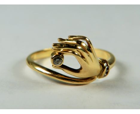 Unusual ring with a hand holding a CZ Stone bears the marks 750.  Finger size 'O'  2.4g