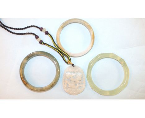 A modern carved jade pendant on braid necklace and three Chinese jade bangles, (interior diameter 5.8cm), (4).