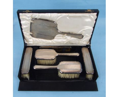 A six-piece engine-turned dressing table brush set in fitted case.