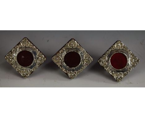 A set of three Edwardian silver miniature easel photograph frames, each embossed with a border of scrolls, 4cm wide, Birmingh