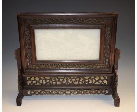 A Chinese pale jade and hardwood table screen, the rectangular panel carved in high relief with a lakeside scenes of carp spr