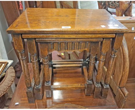 A vintage stained oak nest of three tea tables, set on turned supports