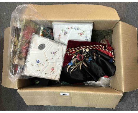 A box containing vintage textiles including a small piece of handmade patchwork, lady's handkerchief gift sets, a black embro