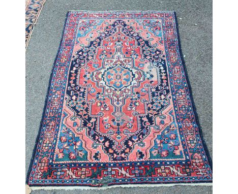 An Eastern handmade wool rug with large central medallion within a single border on red and blue ground - 1.96m X 1.3m