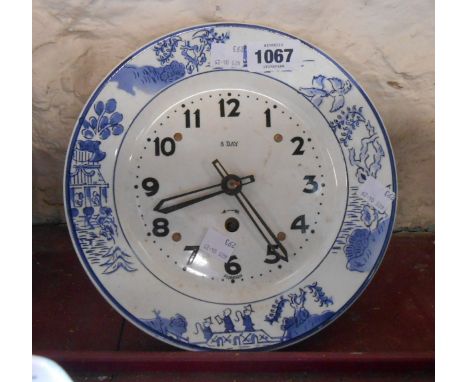 An early 20th Century ceramic kitchen clock of plate form with stylised transfer printed border and eight day movement