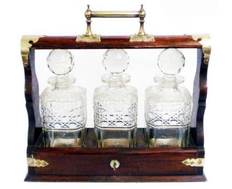 An oak and brass bound tantalus containing three cut glass decanters