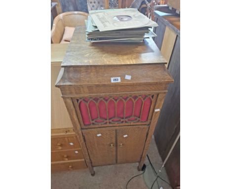 A Brunswick oak cased freestanding gramophone with record storage enclosed by a pair of doors- sold with a small selection of