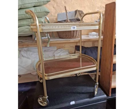 A vintage brassed metal two tier tea trolley, set on casters