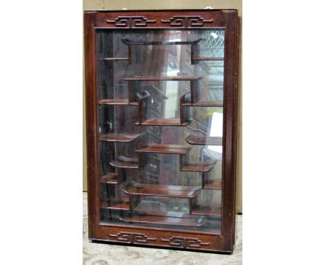 A good quality Chinese hardwood wall mounted display cabinet with carved detail, mirror plate back and enclosing a series of 