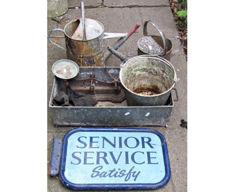 A vintage wall mounted painted aluminium framed sign 'Senior Service Satisfy', together with two galvanised watering cans, bu