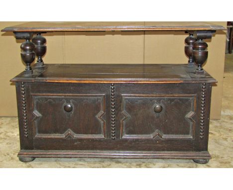 An Edwardian oak monks bench of usual form with rising lid, the box base enclosed by a panelled framework with applied mouldi