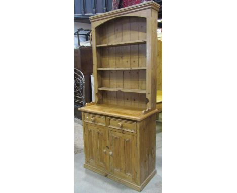 A traditional stripped and waxed pine cottage dresser, the lower section enclosed by two panelled doors and tow frieze drawer