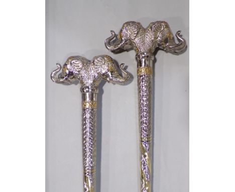 Unusual pair of Indian white metal novelty walking sticks, each with large twin elephant head knops and a good tribal walking