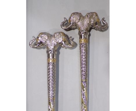 Unusual pair of Indian white metal novelty walking sticks, each with large twin elephant head knops and a good tribal walking