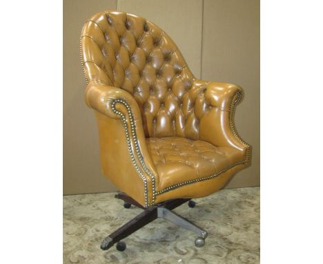 A good quality study chair upholstered in a light tan button back leather with brass stud borders, raised on a swivel base wi