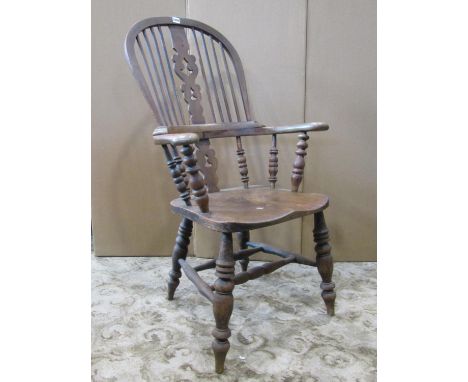 A 19th century Windsor comb back elbow chair with elm seat, shaped and pierced splat and raised on turned supports 