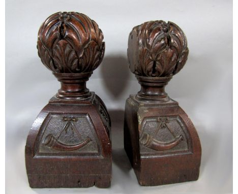 A pair of antique carved oak finials of sprouting blossom upon swept square bases carved with hunting horn panels and poker w