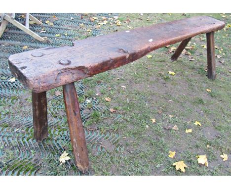 An antique oak bench or form of rustic construction, the heavy plank top raised on four splayed supports, 145cm long x 48cm h