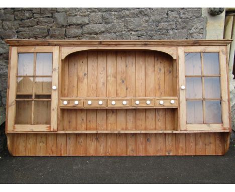 A stripped and waxed pine wall mounted plate rack, the central section with arched outline incorporating five spice drawers, 