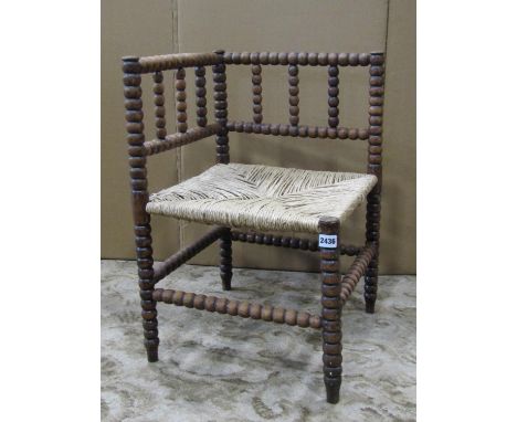 A bobbin moulded corner chair in beechwood with rush seat 