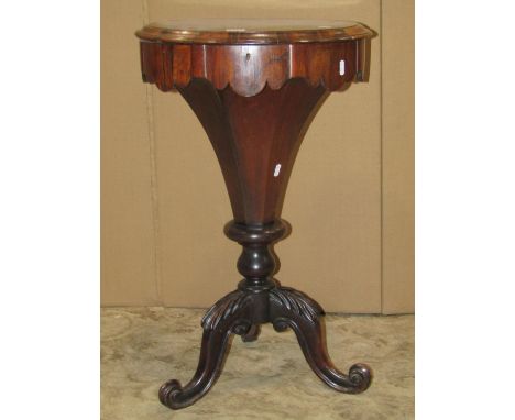 A Victorian rosewood trumpet work box, the circular lid revealing a fitted and segmented interior, raised on a carved and tri