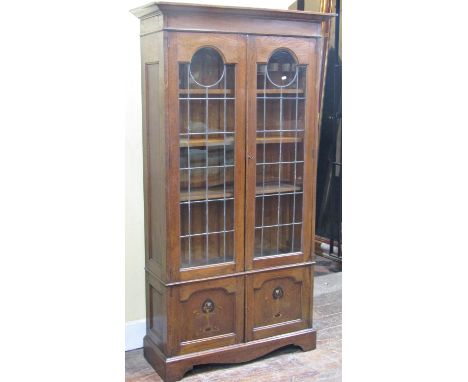 Art nouveau period oak bookcase, the lower section enclosed by a pair of panelled doors with inlaid botanical detail, the upp