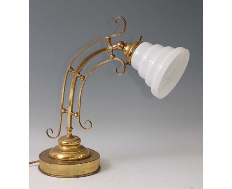 An Art Nouveau lacquered brass table lamp, having a honeycomb stepped milk glass shade, with adjustable action, raised on cir