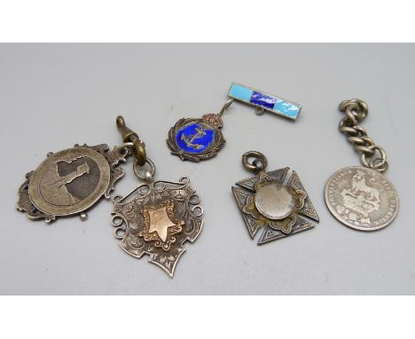 Three silver fobs including one late Victorian golf fob, a silver and enamel badge and a mounted George IV coin, 50g 