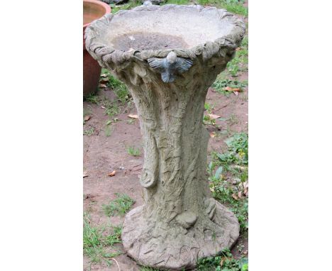 A novelty weathered cast composition stone bird bath in the form of a naturalistic tree trunk with foliate and bird detail, 4