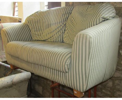 A two seat sofa with shaped outline and repeating green and cream upholstered finish raised on squat oak tapered block feet, 