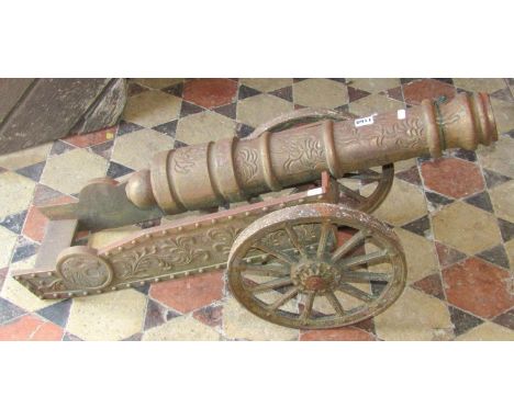 A vintage weathered reproduction cast iron canon and combined two wheeled carriage with decorative embossed scrolling foliate