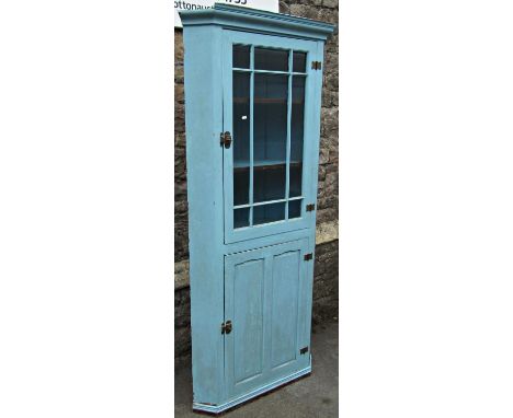 A vintage Georgian style pine floorstanding corner cupboard enclosed by two panelled doors, the upper glazed, (barred) reveal