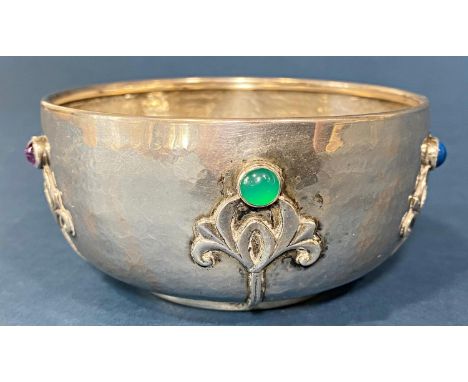 An Arts &amp; Crafts silver sugar bowl with a lightly hammered finish adorned with garnets and stylised flowers, 9 cm diamete