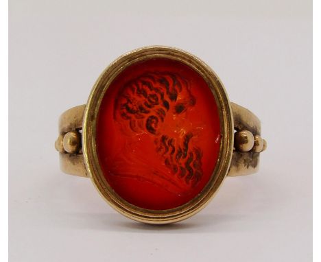 19th century yellow metal intaglio-cut carnelian ring depicting a male bust, with signature below and beaded detail to should