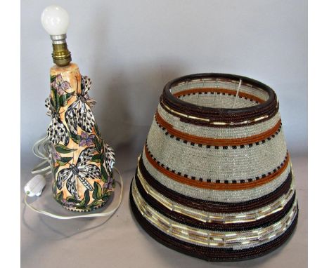 A conical shaped ceramic table lamp with dragonfly decoration with a beaded shade. 