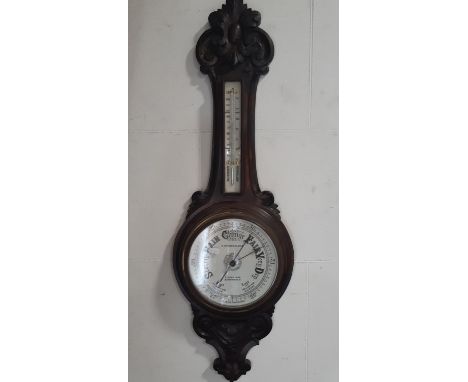 An Edwardian aneroid barometer, the oak case with carved finish with porcelain dials 