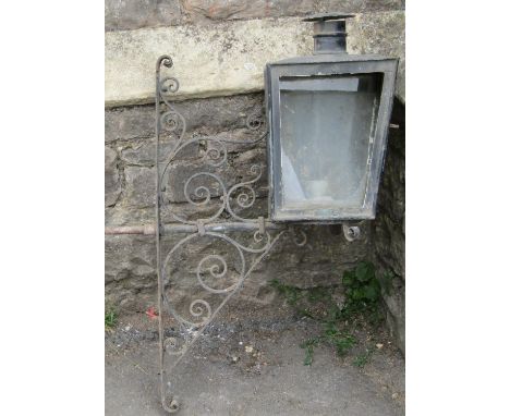 A large cast metal exterior wall mounted electric lantern with domed shade and combined scrolled bracket (for recommissioning